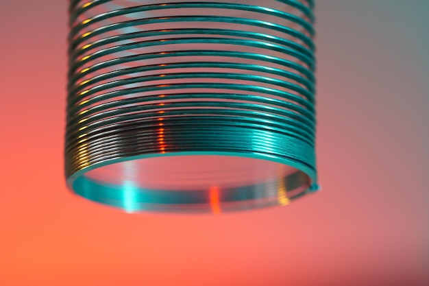 Closeup of coiled metal spring with sufficiently high strength and elastic properties in neon light