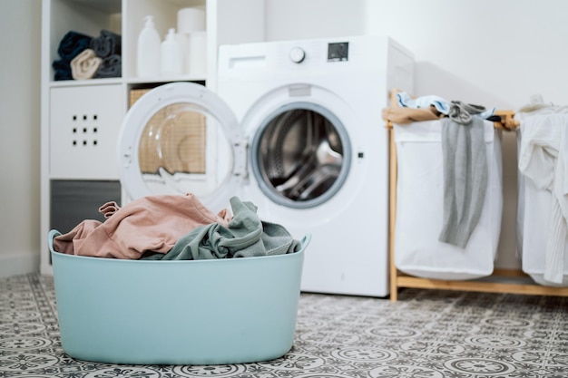 Closeup of colorful clothes in large bowl open washing machine standing in background