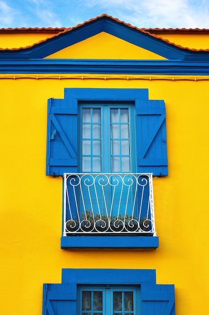 Closeup of colorful Portuguese yellow house facade with old blue windows and wooden shutters in Portugal town Europe Travel and architecture concept Vertical