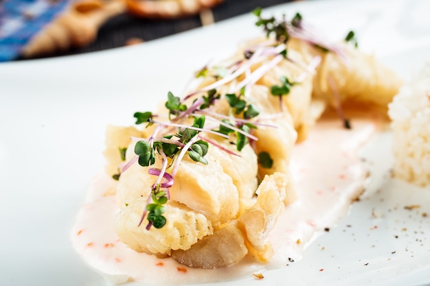 Closeup on cooked white fish fillet with rice on the black wooden table