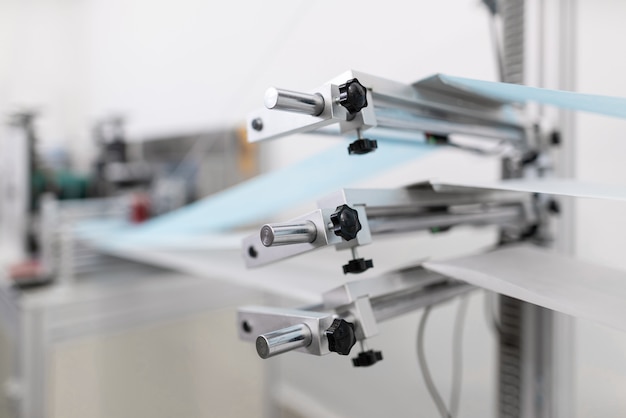 Closeup of cotton fibers merging into a medical face masks in a factory. Automated machinery making respiratory medical masks.