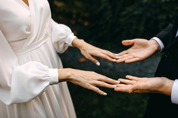 Photo closeup of a couple of bride and groom holding hands touching fingers