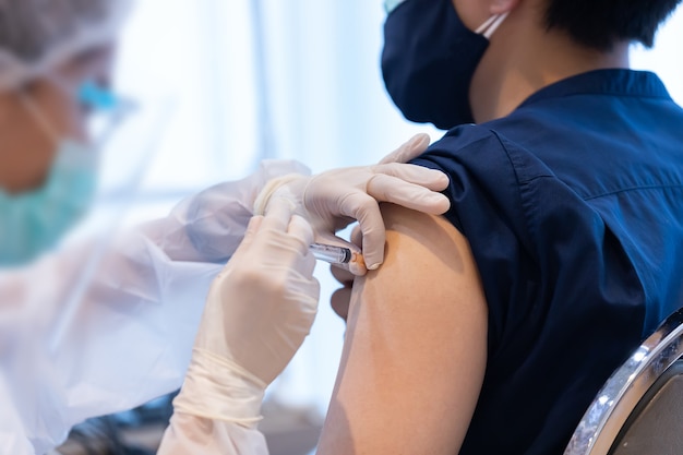 Closeup covid-19 vaccine injecting into patient arm shoulder with single use plastic syringe by doctor, Boost the immune system with inactivated or adenovirus virus