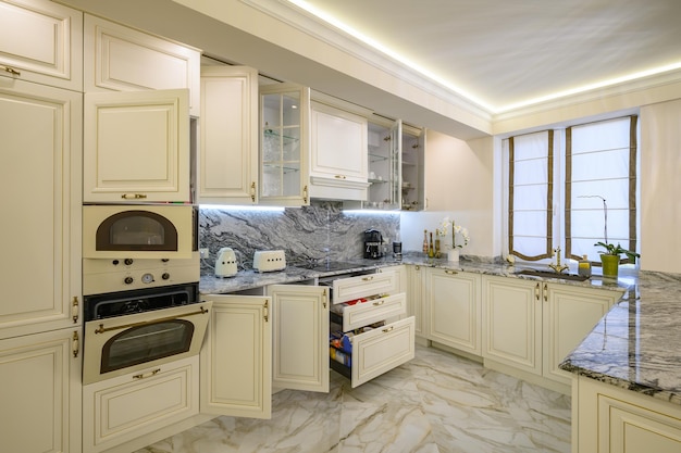 Closeup of a creamcolored kitchen drawers extended and cabinet doors open