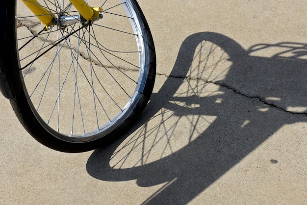 Closeup of crooked bicycle wheel, projecting surreal shadow on sidewalk