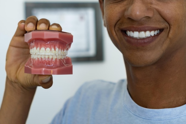 Closeup cropped image of a young man showing a mockup of teeth