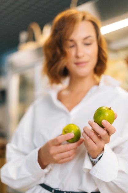 Closeup cropped shot of attractive young woman holding in hands lime posing standing at fruit and