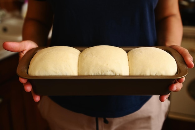 Closeup Cropped view of the hands of a housewife holding a baking container with suitable yeast dough for bread