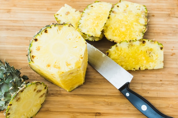 Photo closeup cutting a pineapple on wooden background