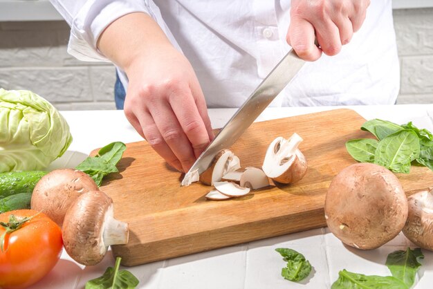 Closeup of cutting slicing fresh mushrooms Womans hands cut with knife fresh mushroom vegetables