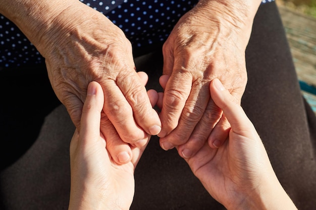 Closeup of daughter's hand holding hands of mother grandmother