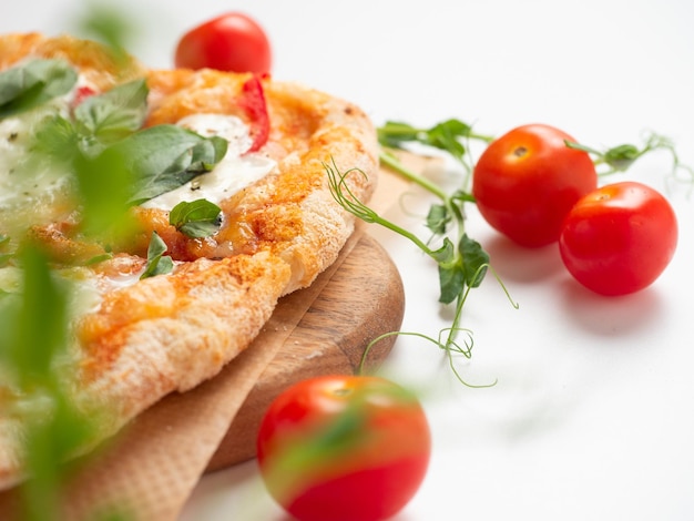 Closeup of a delicious Roman pizza with vegetables on a white background ripe red tomatoes and microgreens lie nearby Traditional Italian food Side view selective focus