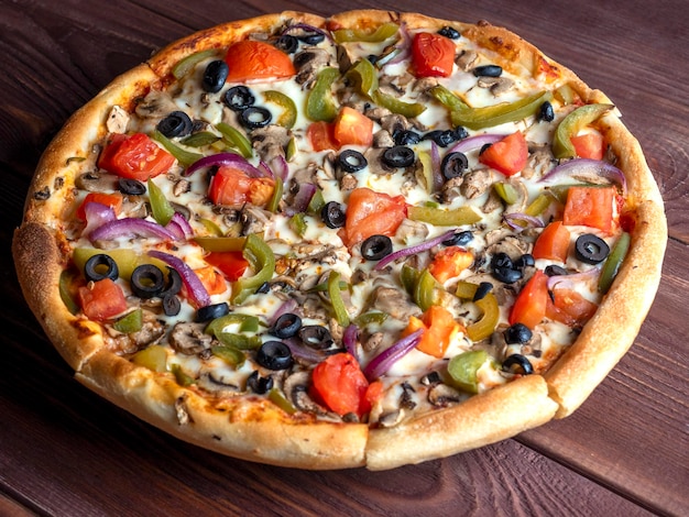 Closeup of a delicious vegetarian pizza with vegetables and mushrooms on a brown wooden background Unhealthy food