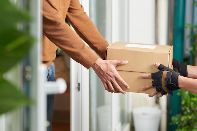 Closeup of delivery man delivering the parcel to the client to home