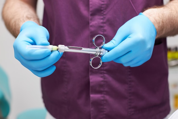 Closeup dental syringe with aneasthetic in dentist doctor's hands