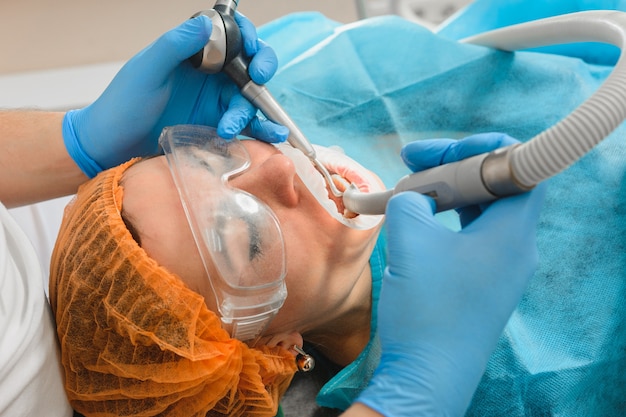 Closeup of dentist young woman removes tartar.