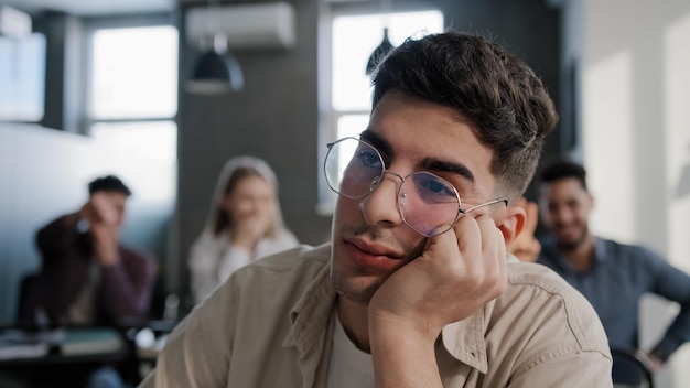 Closeup depressed worried young caucasian guy student sitting at desk alone suffering from bullying