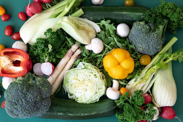 Closeup different bright vegetables on a green background flat lay