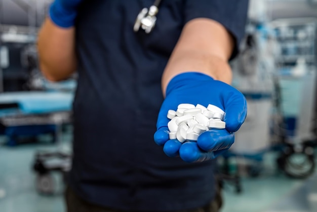 Closeup of doctor in dark blue uniform holding a pills with stethoscope