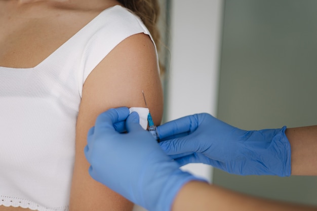 Closeup of doctor in protective gloves holding syringe and using cotton before make injection to