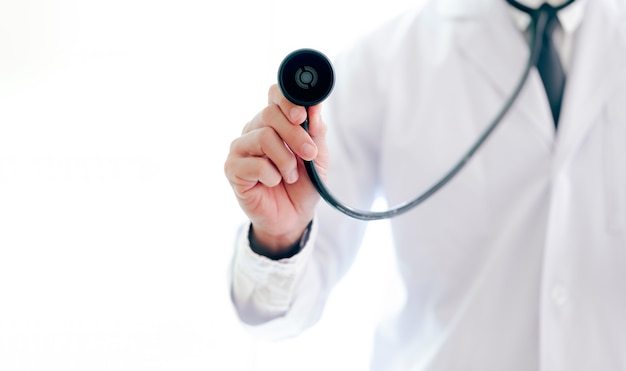 Closeup doctor's hand holding a stethoscope outstretched towards the viewer