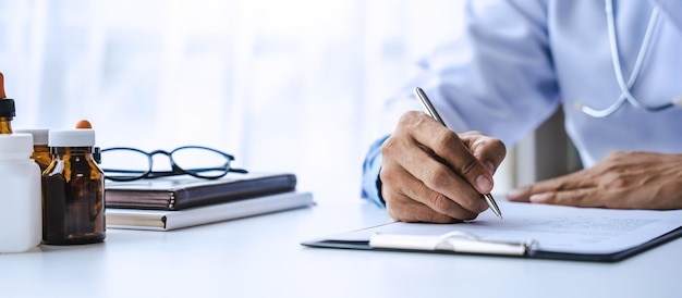 Closeup of doctor's hands writing prescription with bottle with pills Healthcare medical and pharmacy concept