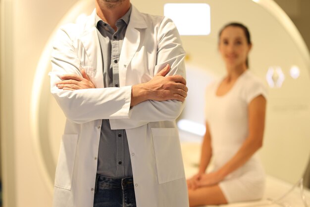 Closeup of doctor standing closeup and blurred patient and ct scanner in background mri tests