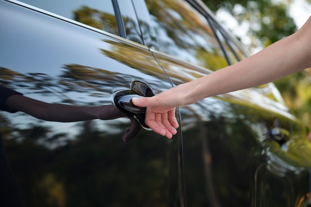 Closeup of driver hand opening car front door with touch ID finger imprint scanning technology Vehicle safety concept