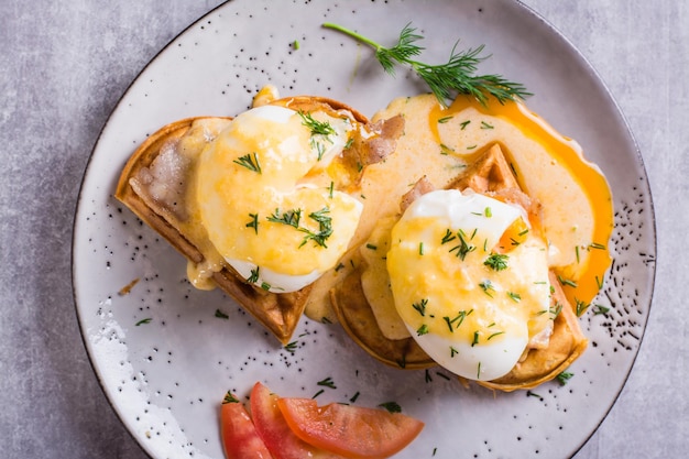 Closeup of eggs benedict and bacon on a crispy waffle for homemade breakfast Top view