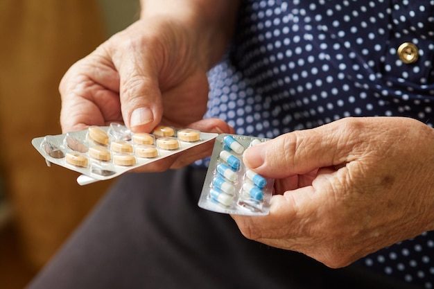 Closeup of an elderly woman's hand preparing to take pills from a blister pack