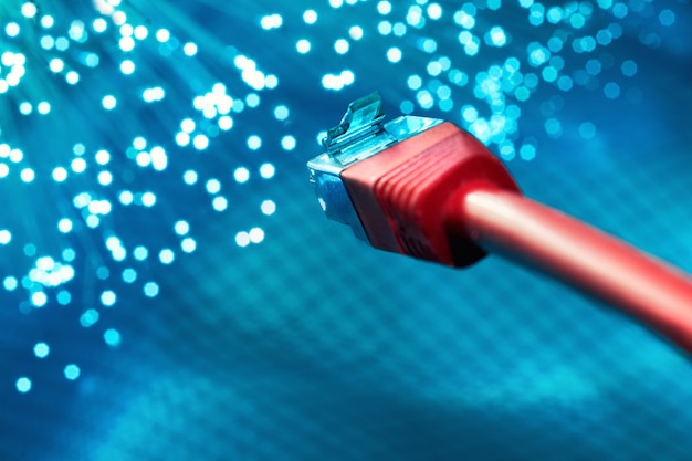 Closeup on the end of red optical fiber network cable on blue background