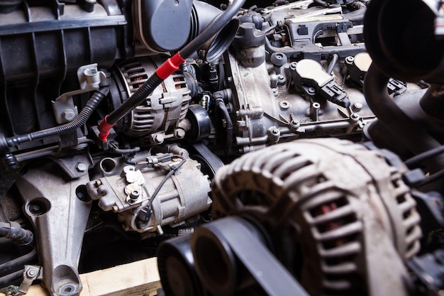 Closeup of an engine with a generator and attachments on a background of metal parts in the dark in a car service Background for a parts store or workshop