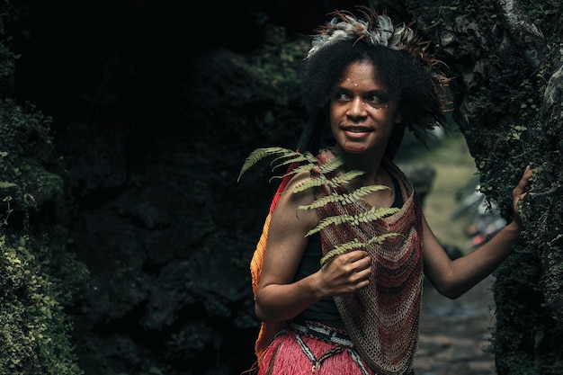 Closeup of exotic young Papua girl of Dani tribe in traditional clothes is smiling in the middle o