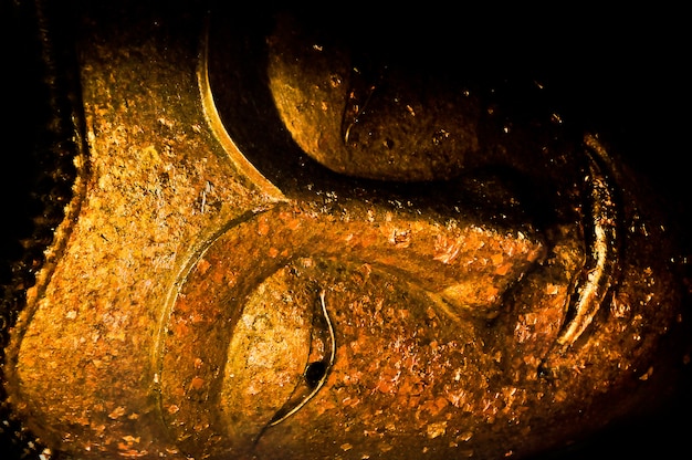 Closeup of the face of buddha's image covering with gold leaf