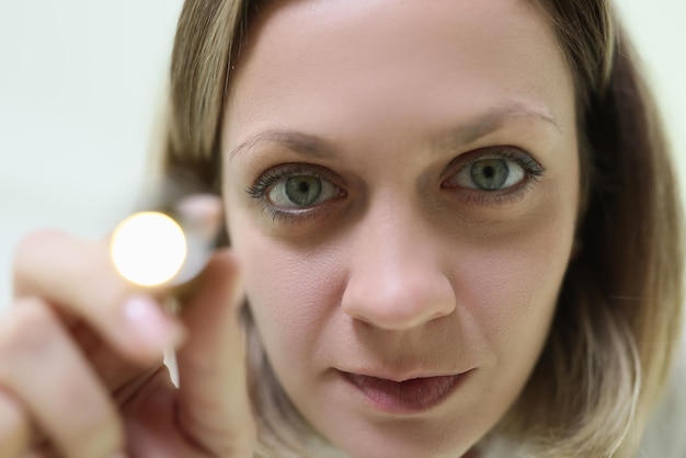 A closeup face of a young woman with a flashlight medical diagnostics ophthalmological study