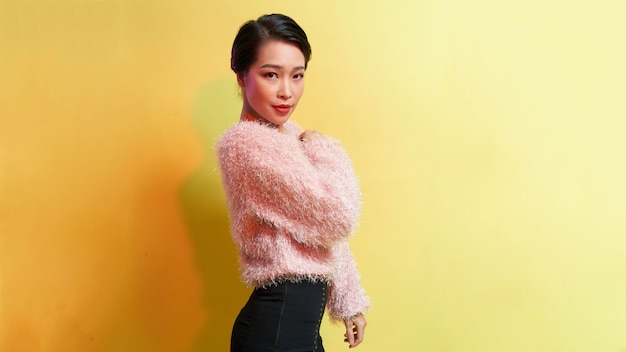 Closeup Fashion woman portrait of young pretty trendy girl posing against the backdrop of a yellow wall