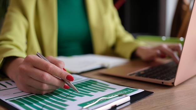 Closeup of female accountant working with statistics data and typing on modern laptop paperwork