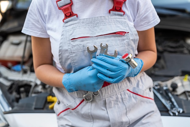 Closeup of a female auto mechanic checking a car engine