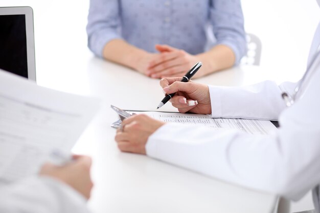 Closeup of a female doctor holding application form while consulting patient