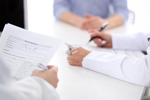 Closeup of a female doctor holding application form while consulting patient