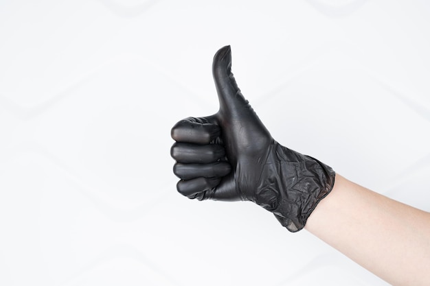 Closeup of female hand in black hygiene pharmacy gloves showing thumbs up sign isolated on white copy space