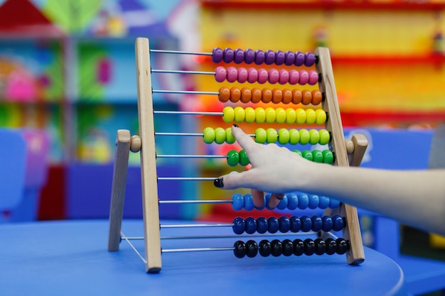 Closeup of female hand calculating  on wooden abacus for number calculation.