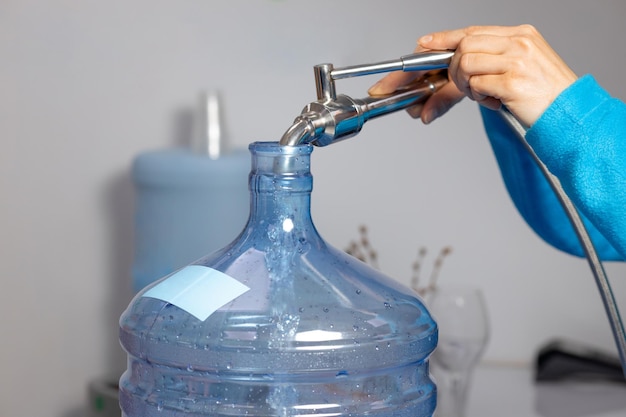 Closeup of female hands pouring water into a bottle at a water filling station