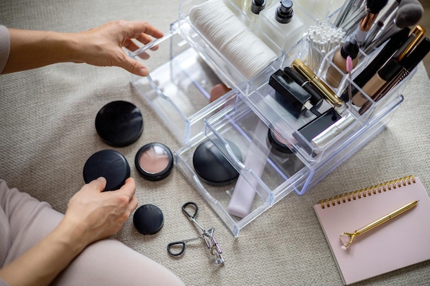 Photo closeup female hands putting luxury cosmetic into acrylic box with drawer storage organization