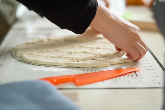 Closeup on female hands and sliced dough on silicone baking mat