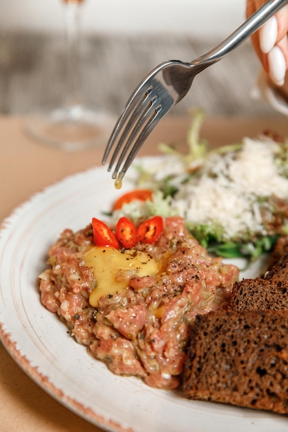 Closeup female hands spread tartare with bread