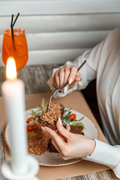 Closeup female hands spread tartare with bread