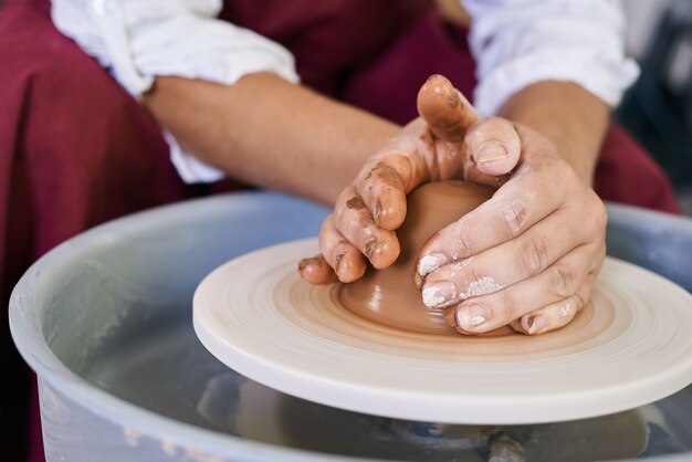 Closeup female hands twist clay on a potter's wheel