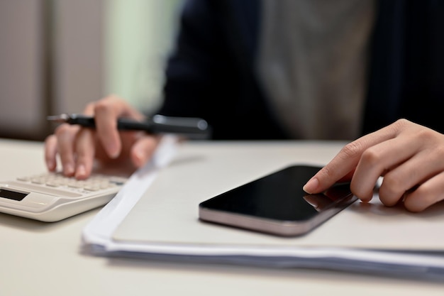 Closeup Female hands typing on cellphone screen and using calculator