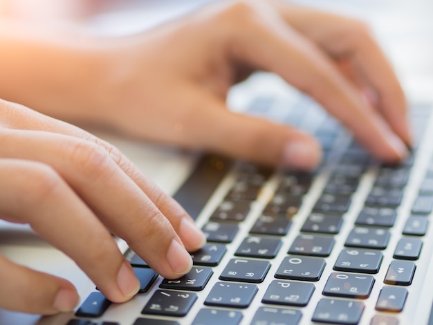 Closeup female hands typing on laptop keyboard.